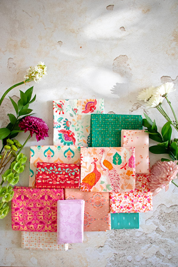 Flatlay aller 12 Stoffe des Paradise Garden Fat Quarter Bundles von Art Gallery Fabrics mit Pfauen-, Floral- und Ikat-Drucken